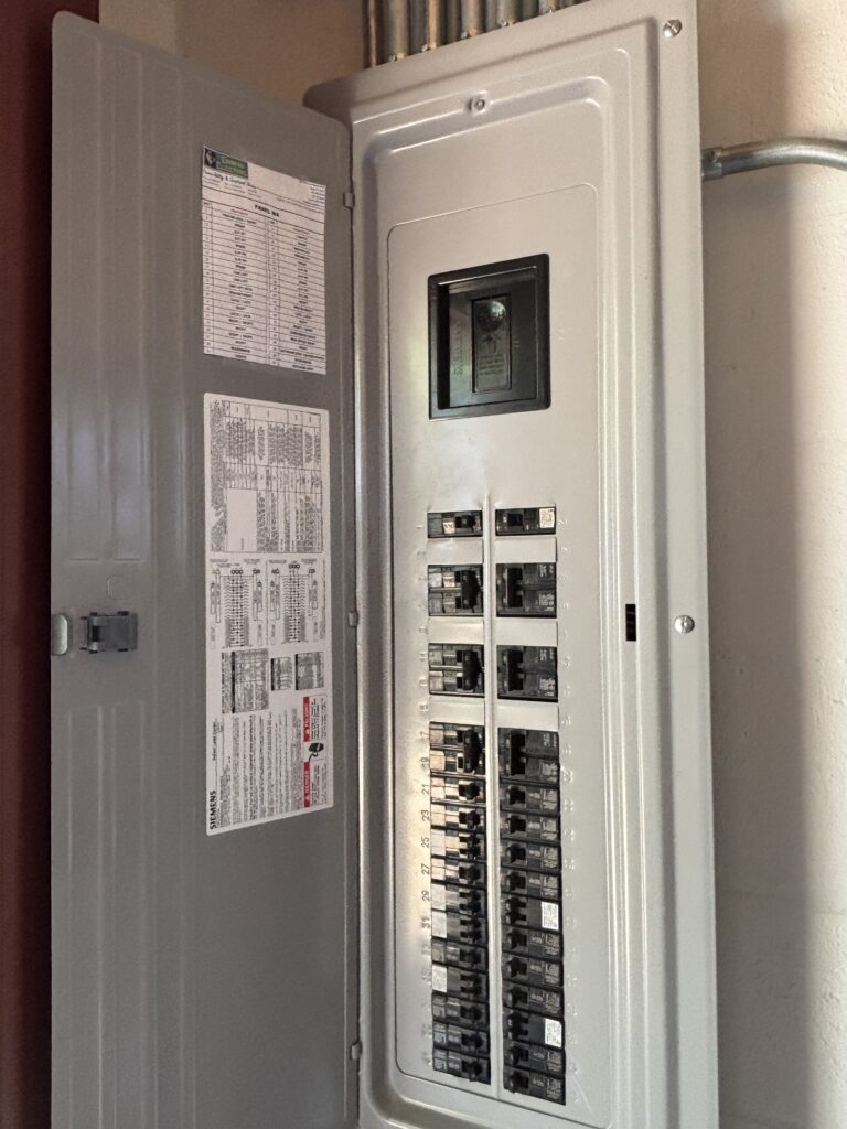 Open residential electrical breaker panel with switches