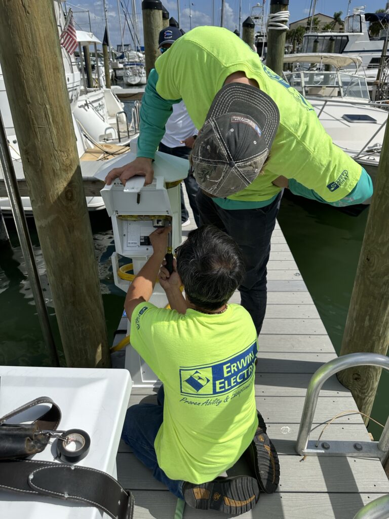 Two electricians repairing marina dock electrical box